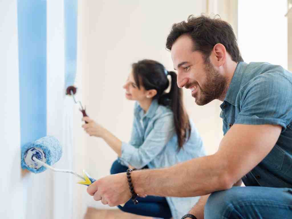a man and woman painting a wall