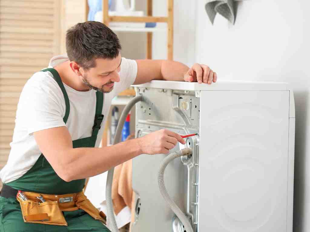 a man in overalls fixing a washing machine